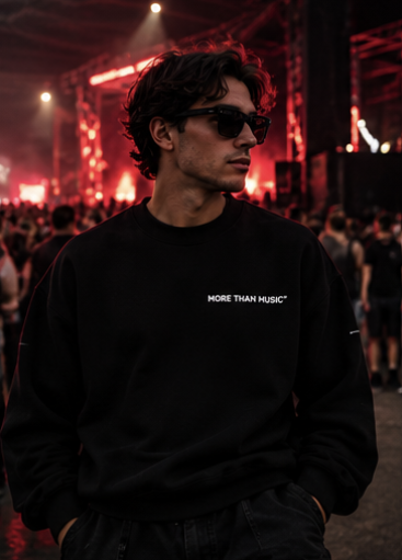 Model wearing a black crew-neck sweatshirt with small white More Than Music chest lettering